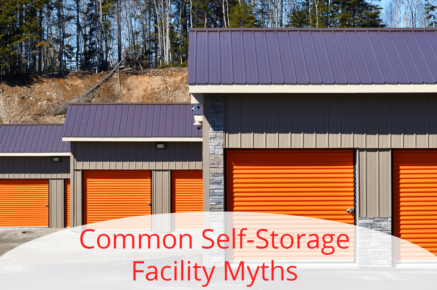 Three self storage facility buildings with orange doors lined up, receding into the back.