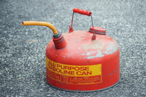 A red can of gasoline sitting on gray asphalt, something you cannot put in a self storage facility.