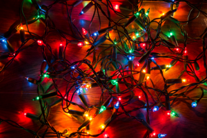 Candy colored Christmas lights lit up and tangled on the floor - not ready to be placed in holiday decor storage.